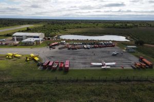 Vista aérea de uma base de combate a incêndios, com aviões, caminhões e equipes de emergência mobilizadas.